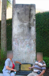 wall in 2009, paint very faded. Two people sit in front of it, faces blurred